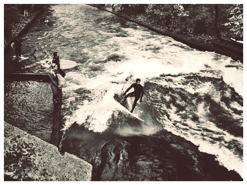 Instead of walking over sand dunes looking for waves, Pat and Tanner found themselves in the middle of a German city looking for a river running up through the buildings. They rolled up on a grom in a 4/3 hooded wetsuit with a board strapped to his bicycle, gunning the footpath, and knew they’d found The Eisbach, tucked away in the heart of one of Germany’s biggest cities (Munich). The banks are packed with Munich’s surf crew braving the cold to get a few turns in before work. Surfing the river break in autumn allowed the Gudangs to see the local crew of surfers gathered at the flowing wave – they narrowly avoided the colder winter months where they would’ve had to hammer away the ice to get in place for a set.